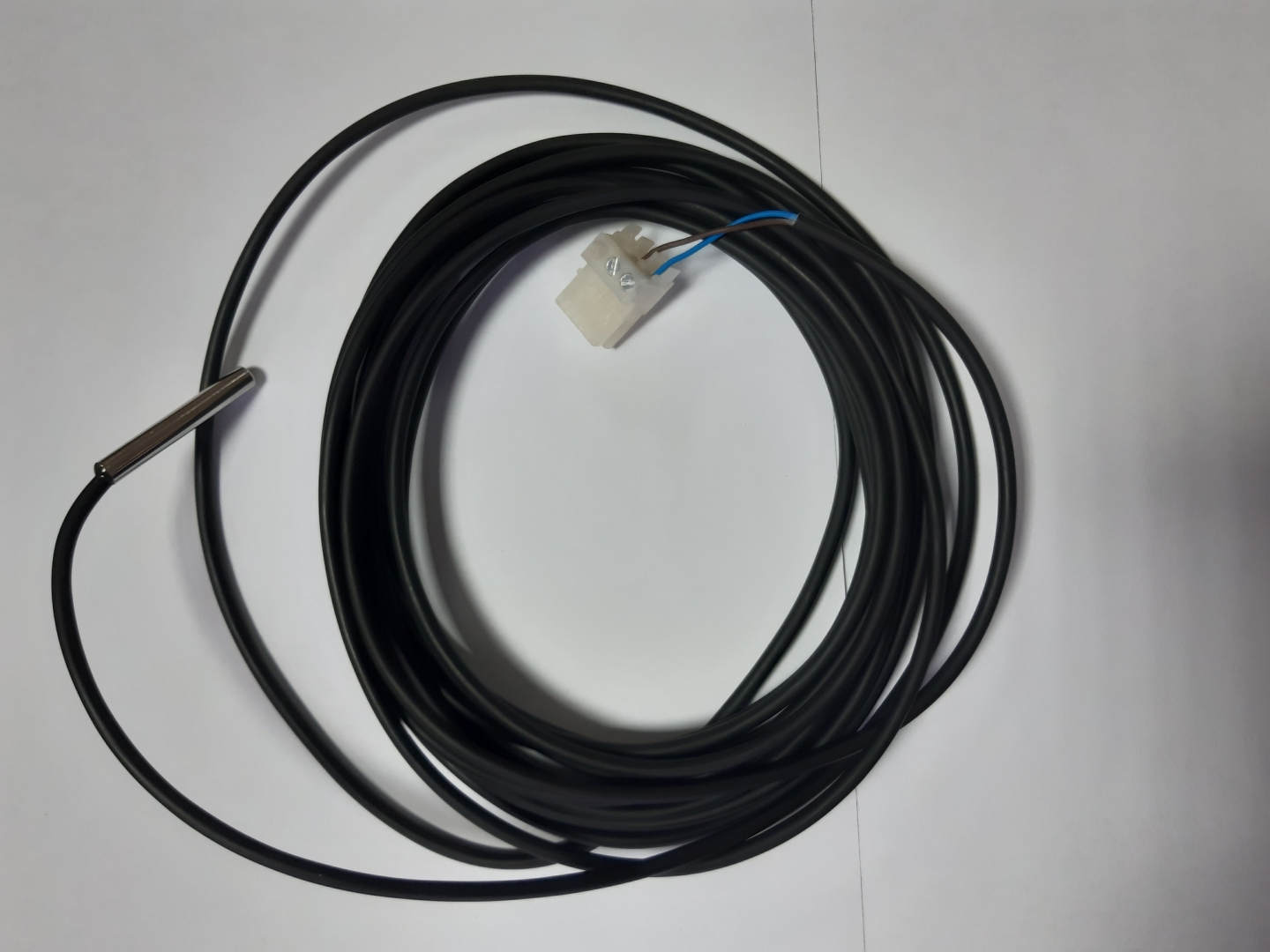 Bosch-senzor-sett-ntc-rd-6_0-12k-6000-nk2_x - Solarplaza Long black temperature sensor cable with metal probe at left and a white 2-pin connector with blue and brown wires in the middle. - Solarplaza