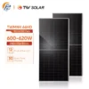Two black solar panels standing upright next to an orange data card showing 600-620W, Mono 132 Cells, and warranty details (12‑year product, 30‑year power).